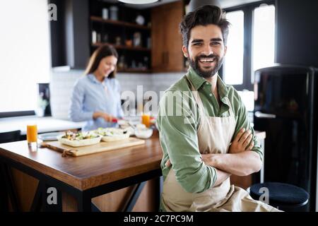 Portrait of happy young couple cooking together in the kitchen at home. Stock Photo