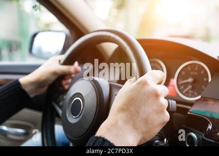 Close up of man hands driving a car during sunlight. Vintage filter Stock Photo
