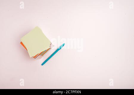 A box with colorful papers and a blue pen isolated on a light-colored background Stock Photo