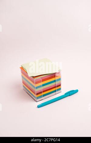 Vertical shot of a box with colorful papers and a blue pen isolated on a light-colored background Stock Photo