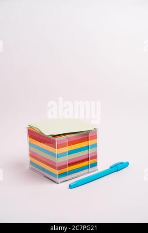 Vertical shot of a box with colorful papers and a blue pen isolated on a light-colored background Stock Photo