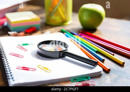 Back to school: note book, pencils, loupe, green apple on wooden table Stock Photo