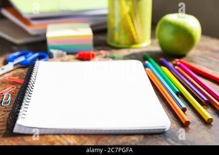 Back to school: note book, pencils, loupe, green apple on wooden table Stock Photo