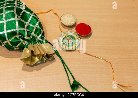 Indian festival, Raksha Bandhan background with an elegant colorful Rakhi, Gift, Rice Grains and Kumkum. Indian festival of Brothers and Sisters. Stock Photo