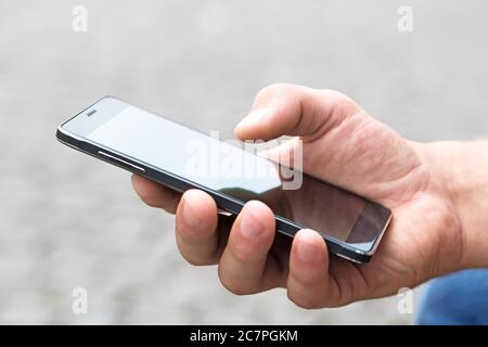 Man using his Mobile Phone outdoor, close up Stock Photo