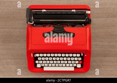 Red mechanical typewriter with white keys on wooden table Stock Photo