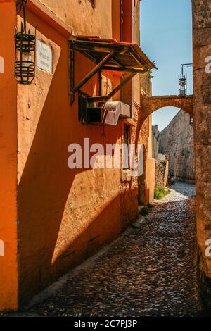 Narrow cobblestone street in the old citycentre of rodos  greece. The street has old lanterns hanging on the walls ends in the background the street e Stock Photo