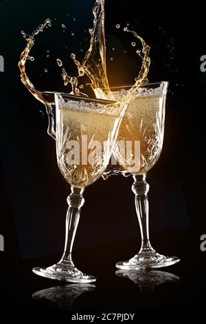 Clinking glasses of champagne with splash on dark background Stock Photo