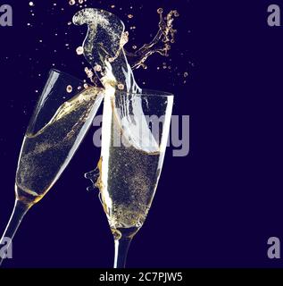 Clinking glasses of champagne with splash on dark background Stock Photo