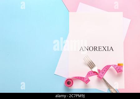 Paper sheet with text ANOREXIA, measuring tape and fork on color background Stock Photo