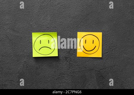 Sad and happy faces on papers against dark background Stock Photo