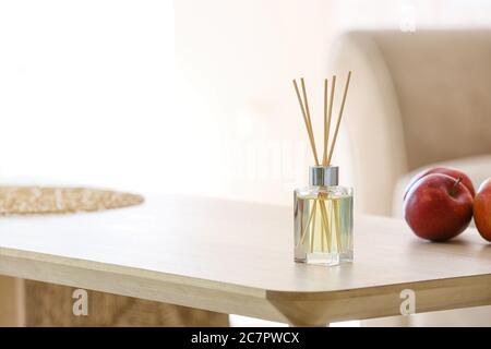 Reed diffuser and apples on table in room Stock Photo