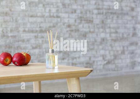 Reed diffuser and apples on table in room Stock Photo