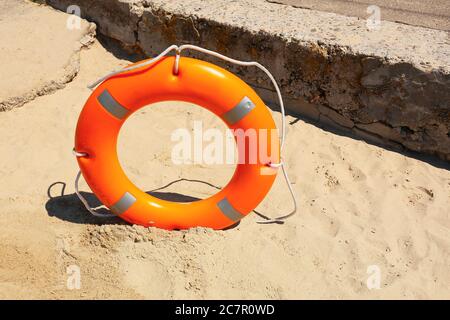 Bright lifebuoy ring on beach Stock Photo