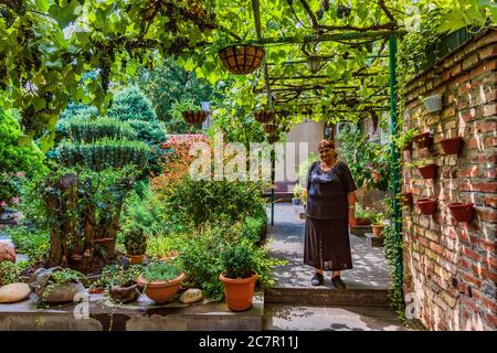 Tbilisi , Georgia - August 25, 2019 :  one old woman posing in the backyard garden of his house in the old town Stock Photo