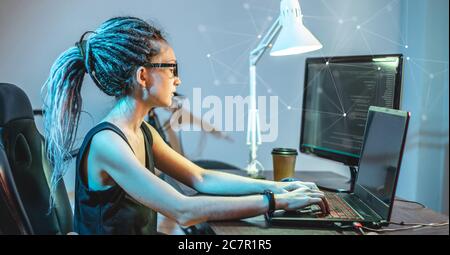Modern young female programmer is writing program code on a laptop at home. Remote work in the IT profession. The concept of software development. Stock Photo