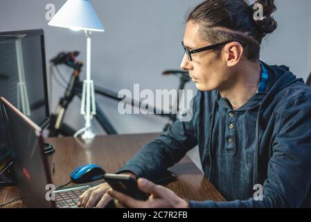 Male programmer is writing program code on a laptop at home. Remote work in the IT profession. The concept of software development. Stock Photo