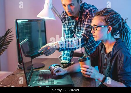 Programmers are developing software by working with software code together. Team work. Modern job of an IT engineer. Stock Photo