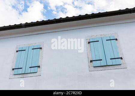 Old traditional house with light blue door and shutters in the village Hrastovlje, slovenia Stock Photo