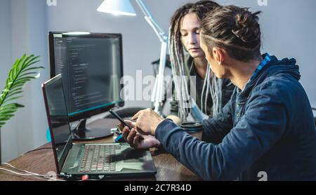 Programmers are developing software by working with software code together. Team work. Modern job of an IT engineer. Stock Photo