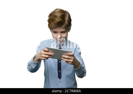 Boy in blue t-shirt enthusiastically plays on the phone. Stock Photo