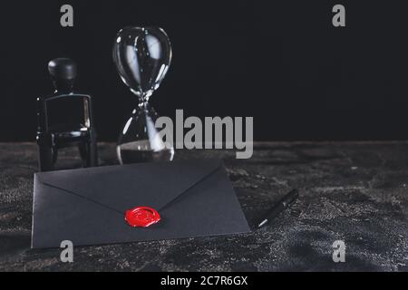 Envelope with notary public wax seal, stamp and hourglass on table Stock Photo