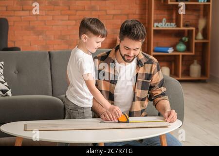 Father and son taking measures of wooden plank at home Stock Photo