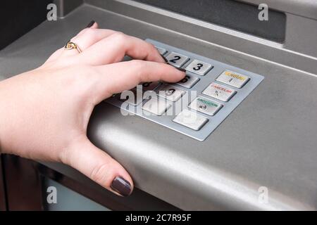 Closeup shot of a female hand with a gold ring pressing buttons on an ATM machine keypad Stock Photo