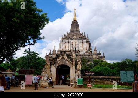 facade of Gawdawpalin Temple under sunny blue sky white clouds. The second highest pahto in Bagan. Local people and tourists walking in and out Stock Photo