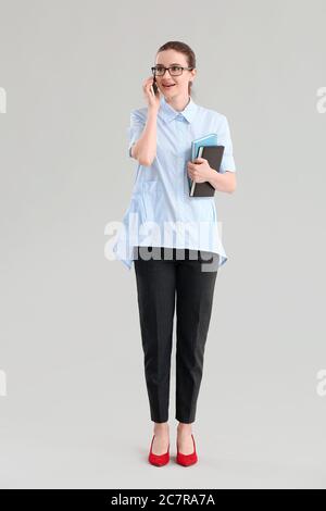 Young businesswoman talking by mobile phone on grey background Stock Photo