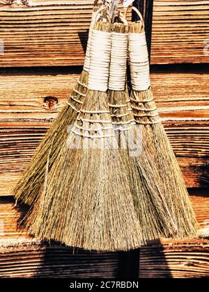 Vertical closeup shot of a group of small natural brooms on a wooden background Stock Photo