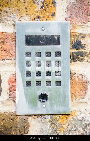 Vertical closeup of an electric doorbell with a camera on a colorful stone wall Stock Photo