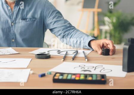 Senior male calligraphist working in office Stock Photo