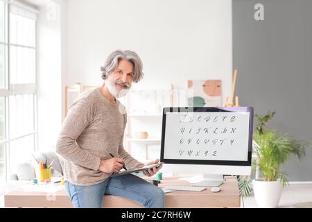 Senior male calligraphist working in office Stock Photo