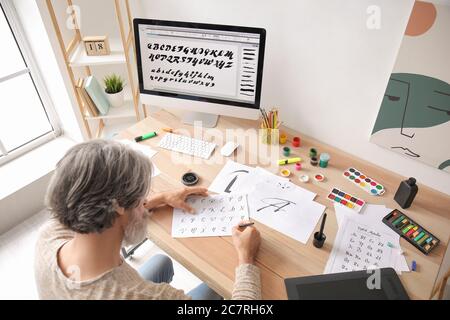 Senior male calligraphist working in office Stock Photo