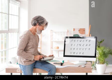 Senior male calligraphist working in office Stock Photo