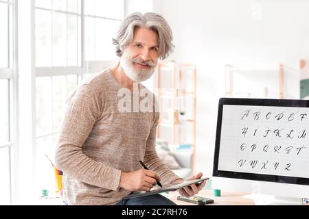 Senior male calligraphist working in office Stock Photo