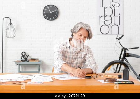 Senior male calligraphist working in office Stock Photo