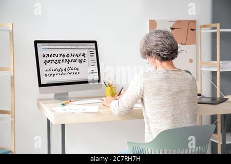 Senior male calligraphist working in office Stock Photo