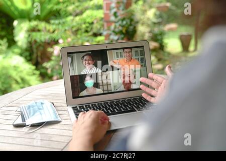Woman having video call and chat with friends via computer laptop at home with garden view Stock Photo