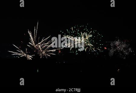 spider rockets and chrysanthemum rocket fireworks exploding as seen from a New York City rooftop on July fourth, 2020 against a black, night sky with Stock Photo