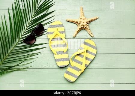 Flip-flops, sunglasses, starfish and tropical leaf on wooden background Stock Photo