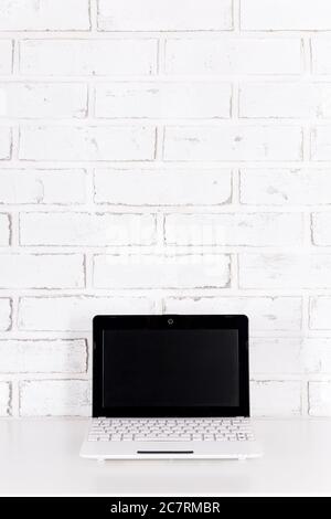 modern laptop on the table over white brick wall background Stock Photo