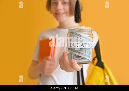 Teenage boy with savings for education on color background Stock Photo