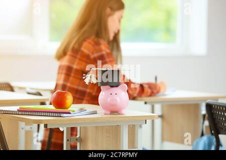 Piggy bank with savings for education in classroom Stock Photo
