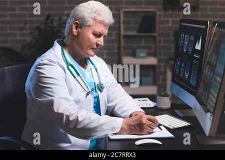 Senior neurologist with MRI scan of human head in clinic Stock Photo