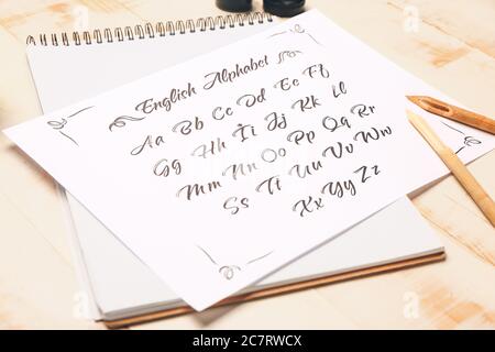 Notebook and paper sheet with alphabet on table Stock Photo