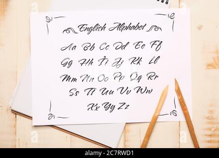 Notebook and paper sheet with alphabet on table Stock Photo