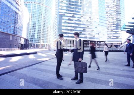 Business people shaking hands standing in a crowd outside office Stock Photo