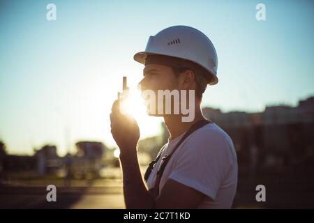 Engineer builder using tablet and walkie talkie, giving instructions at a construction site Stock Photo